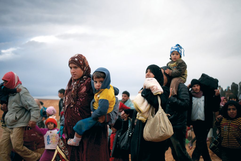 vluchtelingen onderweg met kinderen en bagage op rug