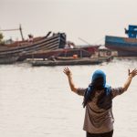 Indonesische vrouw met geheven handen voor rivier